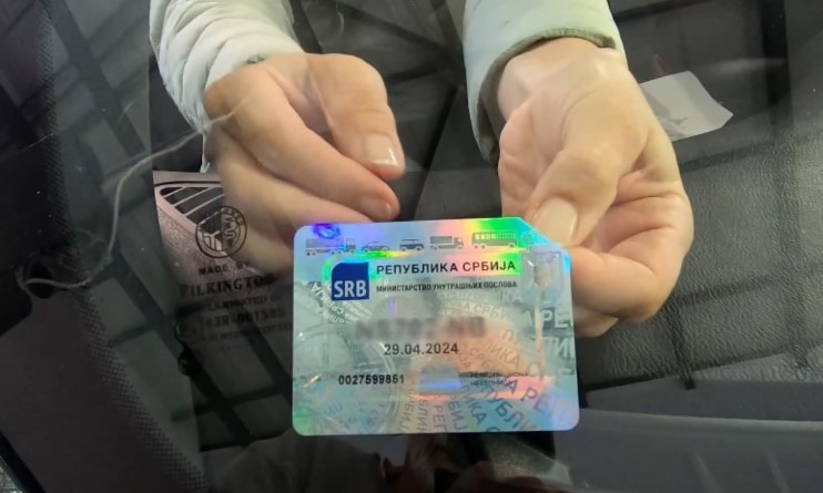 Žena zalepljuje registracionu nalepnicu na šoferku
