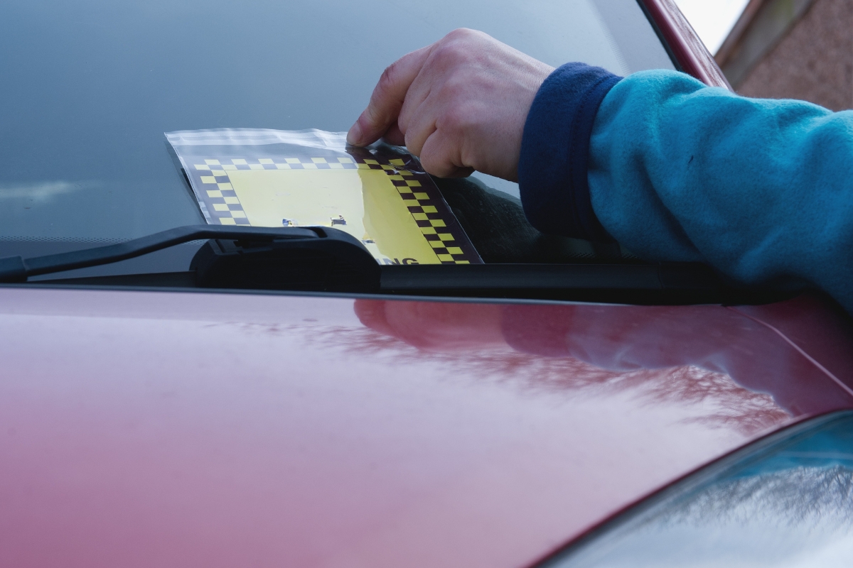 prikaz osobe koja ostavlja kaznu na automobilu